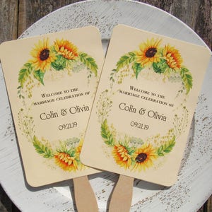 Sunflower wedding fans, personalized for the bride and groom adorned with a circle of sunflowers.  Printed on ivory cardstock with wooden handle hidden between front and back cardstock.  Wedding favor fans come fully assembled.