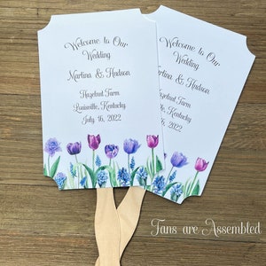 Assembled wedding fans adorned with purple tulips and personalized for your special day.  Keep everyone cool with this cute keepsake.