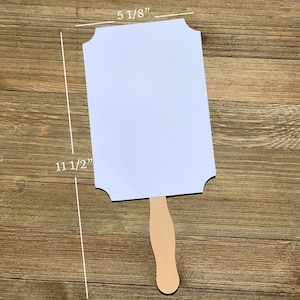 May include: White blank sign with scalloped edges attached to a wooden handle. The sign measures 11 1/2 inches tall and 5 1/8 inches wide.