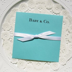 Tiffany Blue baby shower favors, personalized for the new baby.  Each is printed on tiffany blue card stock with a white ribbon tied around, slide a lottery ticket in for a fun and easy baby shower favor.