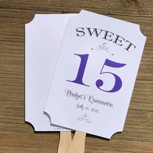 Op de afbeelding: Een witte en paarse waaier met de tekst "SWEET 15 Bridget's Quincea&ntilde;era July 10, 2021" en een decoratief swirl-ontwerp.