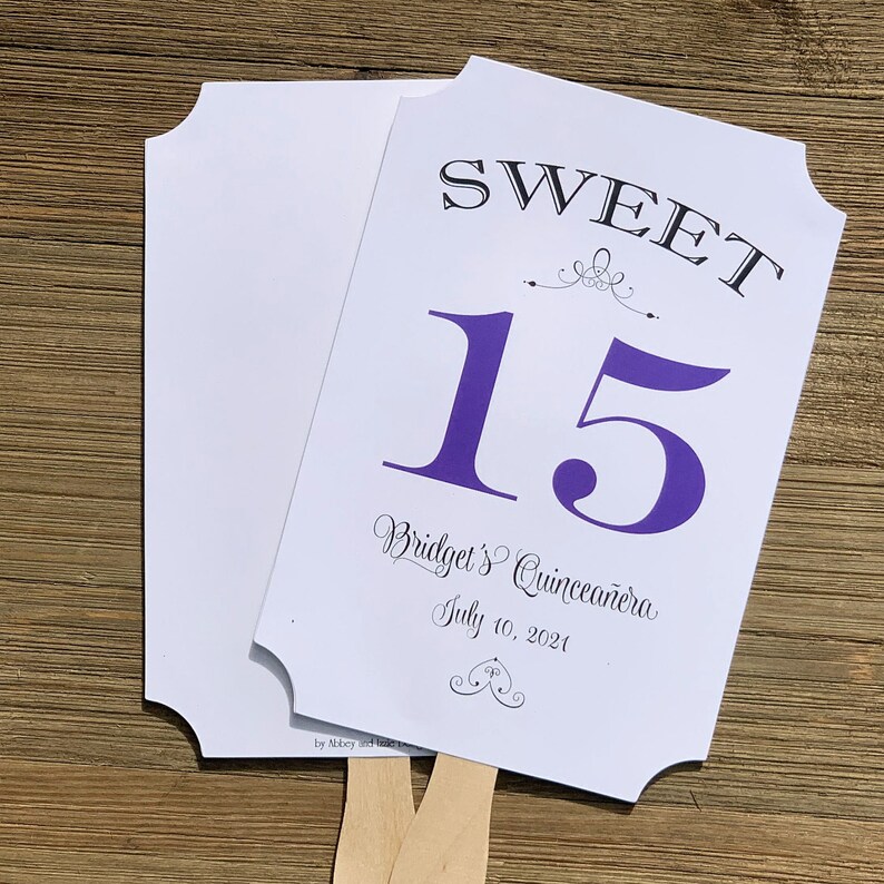 Op de afbeelding: Een witte en paarse waaier met de tekst "SWEET 15 Bridget's Quincea&ntilde;era July 10, 2021" en een decoratief swirl-ontwerp.