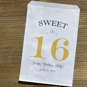 Op de afbeelding: Witte papieren traktatiezak met de woorden "SWEET 16" in zwarte en gouden letters. De zak bevat ook de tekst "Happy Birthday Molly! July 10, 2021". De zak is ontworpen voor een sweet sixteen verjaardag.