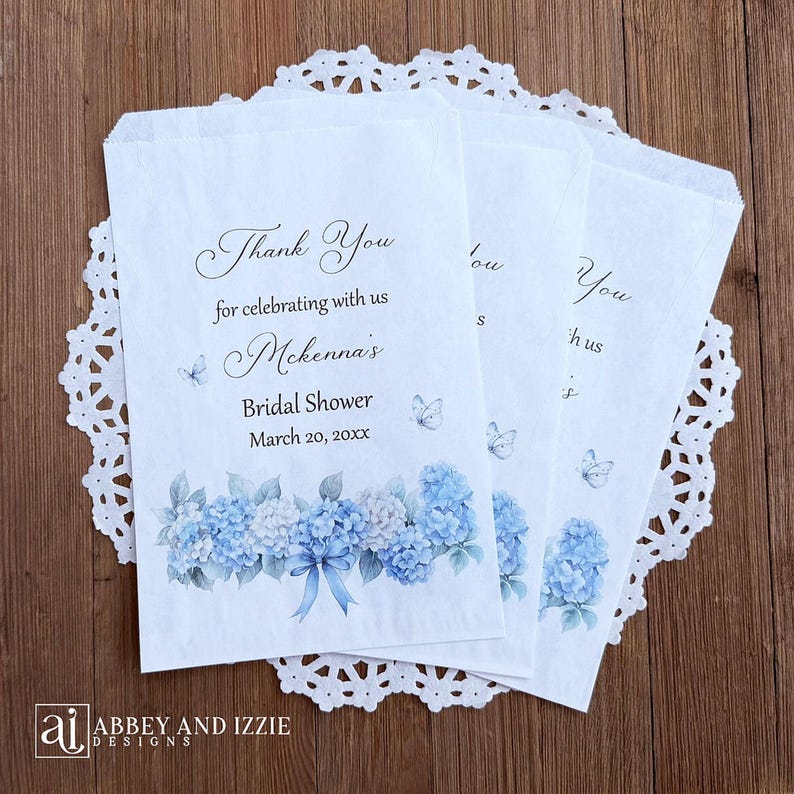 Personalized blue hydrangea bridal shower favor bags, larger than most these bags are perfect for sweet treats including cookie bars or candy buffets.  White bags adorned with delicate blue hydrangeas and butterflies, these will add a touch of elegance to your event.  Printed with 'Thank you for celebrating with us' brides name and event date.