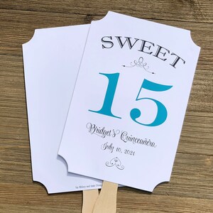 Op de afbeelding: Een witte en turquoise blauwe papieren waaier met de tekst "SWEET 15 Bridget's Quincea&ntilde;era July 10, 2021" en een decoratief ontwerp.