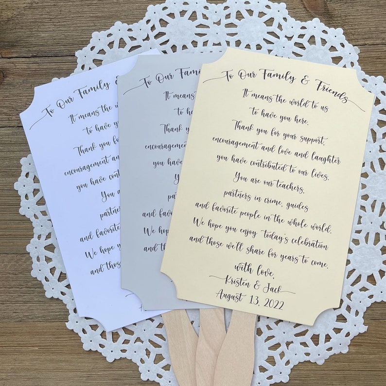 May include: Three wedding fan programs with a light yellow, light gray, and white background. The text on the fans reads "To Our Family & Friends" and includes a message of thanks to guests for their support and encouragement. The fans are decorated with a simple, elegant font. The bottom of the yellow fan includes the names "Kristen & Jack" and the date "August 13, 2022".