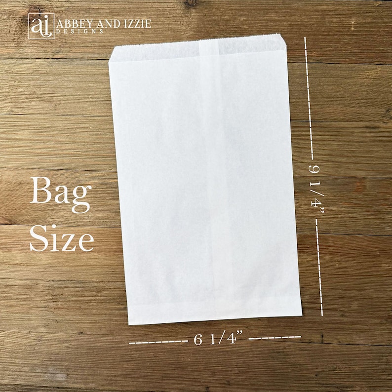 Puede incluir: Una bolsa de papel blanca con el texto "Bag Size" y medidas de 23,5 cm de alto y 15,9 cm de ancho. La bolsa es rectangular y tiene una parte superior doblada. El fondo es una superficie de madera.