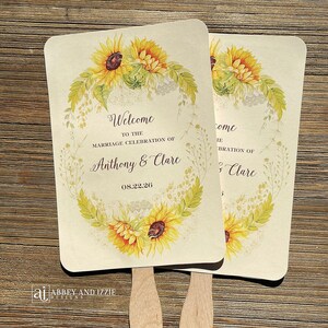 May include: Two wedding fans with a sunflower and greenery design. The fans have the text "Welcome to the marriage celebration of Anthony & Clare 08.22.26" and "Come ie bration of Clare".
