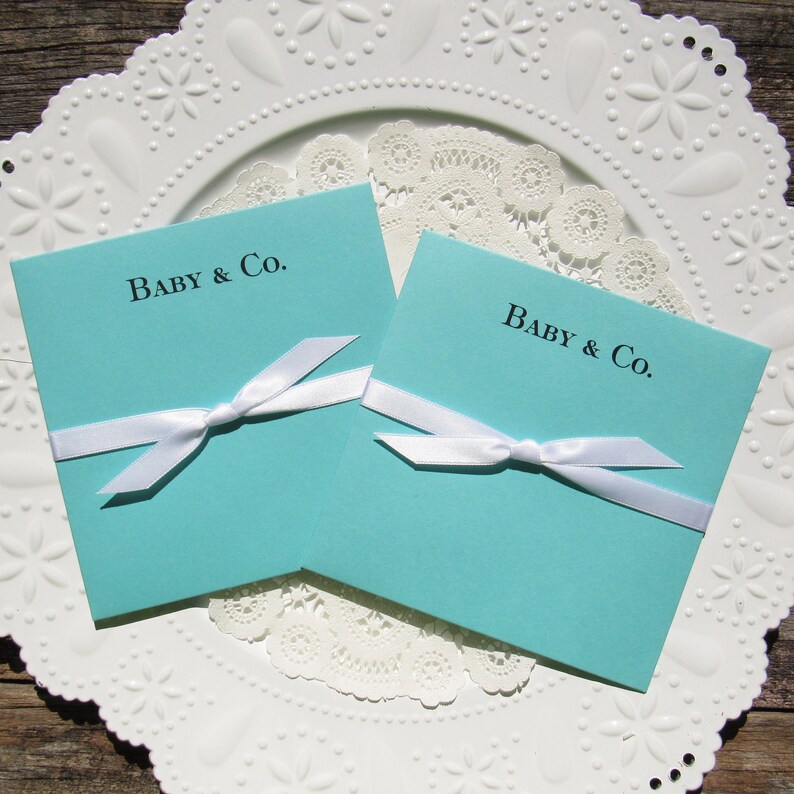 Tiffany Blue baby shower favors, personalized for the new baby.  Each is printed on tiffany blue card stock with a white ribbon tied around, slide a lottery ticket in for a fun and easy baby shower favor.