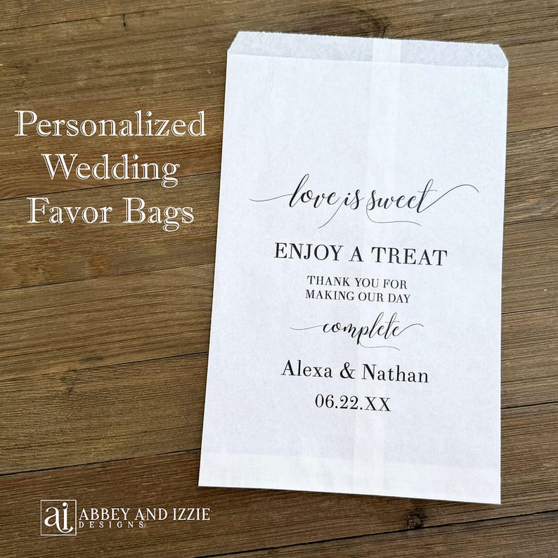 Puede incluir: Una bolsa de papel blanca para recuerdos con el texto "love is sweet" y "Enjoy a treat". La bolsa est&aacute; personalizada con los nombres Alexa & Nathan y una fecha. Tambi&eacute;n son visibles las palabras "Bolsas de recuerdo de boda personalizadas".