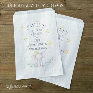 May include: Two white paper favor bags with text and illustrations. The bags read "SWEET OF YOU TO JOIN US!" and "FRINS BABY SHOWER MARCH 23, 20XX". An illustration of a baby elephant with a crown is featured.