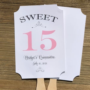 Op de afbeelding: Een witte papieren waaier met een roze nummer 15, de woorden "SWEET" en "Bridget's Quincea&ntilde;era" en de datum "July 10, 2021".