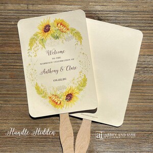 May include: Two wedding fans with a sunflower and greenery design. The text on the fan reads "Welcome to the marriage celebration of Anthony & Clare 08.22.26".