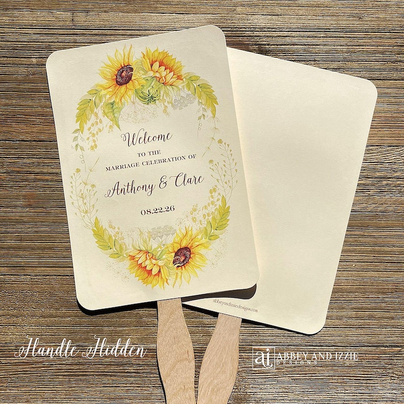 May include: Two wedding fans with a sunflower and greenery design. The text on the fan reads "Welcome to the marriage celebration of Anthony & Clare 08.22.26".