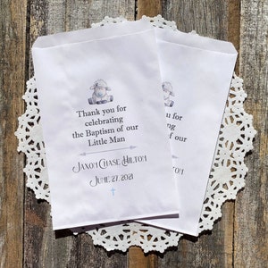 K&ouml;nnte beinhalten: Wei&szlig;e Geschenkt&uuml;ten mit einer blauen Lamm-Illustration und dem Text "Thank you for celebrating the Baptism of our Little Man Jaxon Chase Hilton June 27, 2021 +" darauf gedruckt.