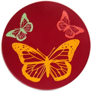 May include: A red round silicone coaster with three butterfly designs. The butterflies are in shades of green, orange, and pink.