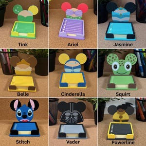 May include: A collection of nine character-themed sticky note holders, each featuring a unique design inspired by popular figures like Tink, Ariel, Jasmine, Belle, Cinderella, Squirt, Stitch, Vader, and Powerline, with colourful bases and paper pads.