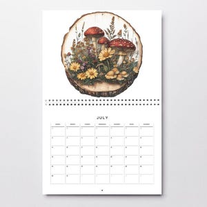 May include: A July calendar page with a wood slice illustration featuring red and white mushrooms, yellow flowers, and green leaves. The month of July is printed at the top of the calendar.