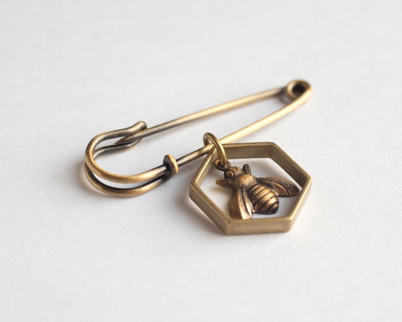 a bee in hexagon brass pin on a white background