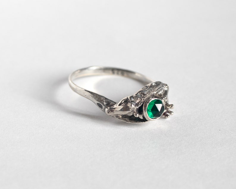 two giraffes ring in silver with rose cut emerald, laying at an angle on a white background