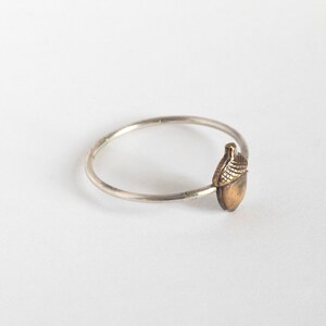 acorn ring on thin silver band, at an angle on a white background