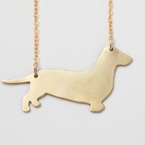 back of brass dachshund pendant, close up on white background.