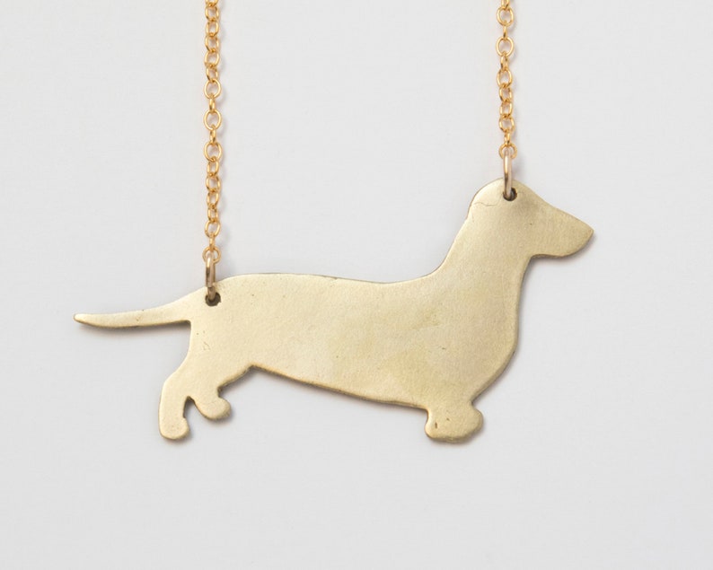 back of brass dachshund pendant, close up on white background.