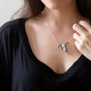 sterling silver elephant head necklace on model wearing black shirt with hand at neck