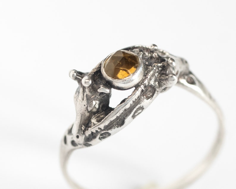 close up of two giraffes ring in silver with rosecut citrine, on a white background