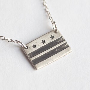 sterling silver washington DC flag necklace, at an angle on white background