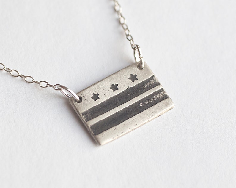 sterling silver washington DC flag necklace, at an angle on white background