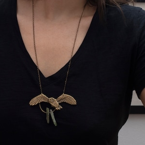 brass barn owl necklace with rough kyanite, on a model in black shirt