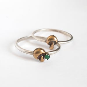 May include: Two silver rings with mushroom-shaped charms. One charm has a green gemstone.