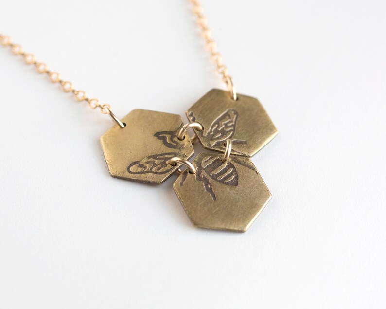 three brass hexagons pendant with etched bee, add an angle on white background