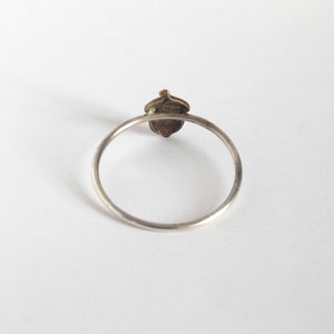 acorn ring on thin silver band, from the back on a white background