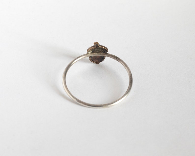 acorn ring on thin silver band, from the back on a white background