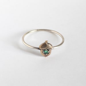 acorn ring with a tiny emerald, on a white background