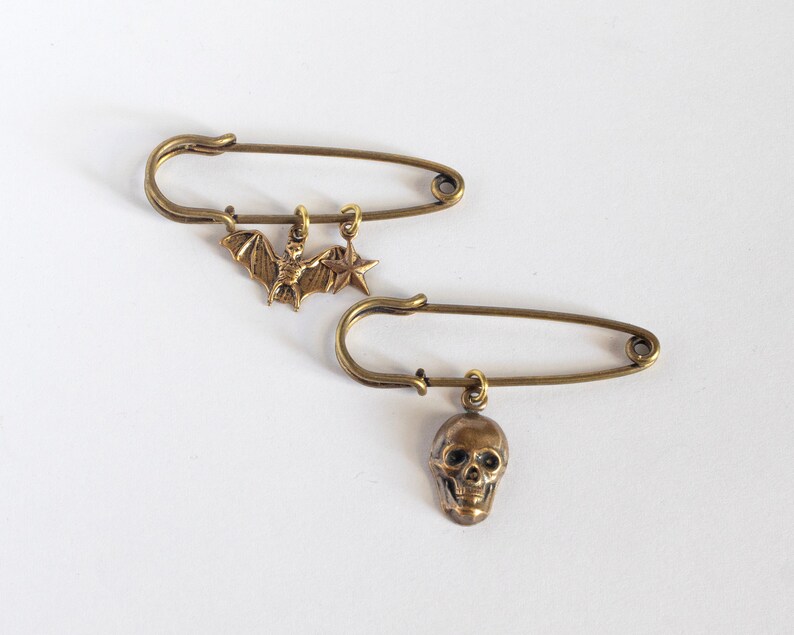 a bat and star charm pin and a skull charm pin on a white background