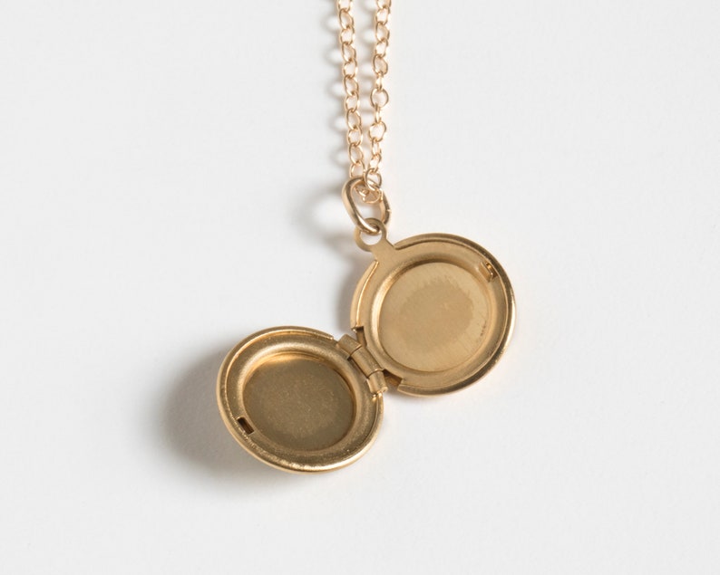 Small gold round locket, shown open on a cable chain, on a white background.