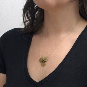 three brass hexagons pendant with etched bee, on a model with white background