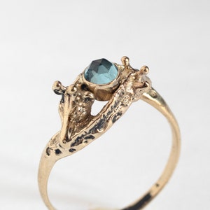 close up of two giraffes ring in gold with rosecut blue topaz, on a white background