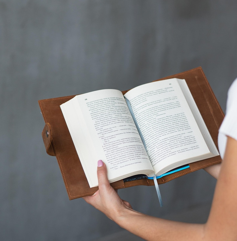 May include: A brown leather book cover with a blue ribbon bookmark. The book is open and the pages are visible.