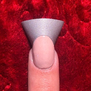 May include: A finger with a light pink nail polish and a silver glitter nail tip.
