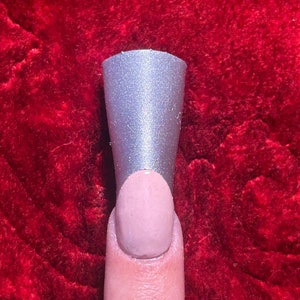 May include: A silver nail tip with a light pink nail polish underneath.