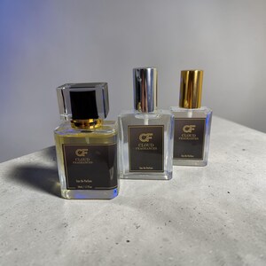 Pu&ograve; includere: Tre flaconi di profumo con vetro trasparente e tappi metallici. Ogni flacone ha un'etichetta marrone scuro con la scritta "CF CLOUD FRAGRANCES". I flaconi sono riempiti con un liquido color ambra chiaro. Il flacone anteriore ha un tappo nero ed &egrave; etichettato "Eau De Parfum 50ml / 1.7 fl oz".