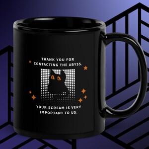 May include: Black ceramic mug with a curved handle. The mug features the text "THANK YOU FOR CONTACTING THE ABYSS. YOUR SCREAM IS VERY IMPORTANT TO US." along with a graphic of a black cat with orange eyes.