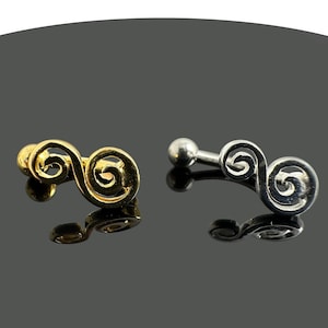 Puede incluir: Dos anillos de nariz con un diseño de doble espiral. Uno es dorado y el otro es plateado.