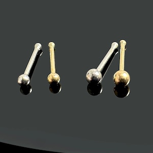 Peut inclure: Trois anneaux de nez avec des extrémités en boule. Un est argenté et deux sont dorés.