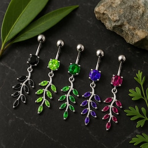 Puede incluir: Cinco piercings para el ombligo con tallos plateados y detalles de piedras preciosas de colores. Cada anillo presenta una piedra preciosa de diferente color: negro, verde, verde esmeralda, morado y rosa. Las piedras preciosas se combinan con dijes en forma de hojas.