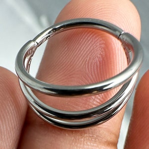 Könnte beinhalten: Ein silberner Doppel-Hoop-Ohrring mit nahtlosem Design. Der Hoop besteht aus zwei separaten Ringen, die miteinander verbunden sind.